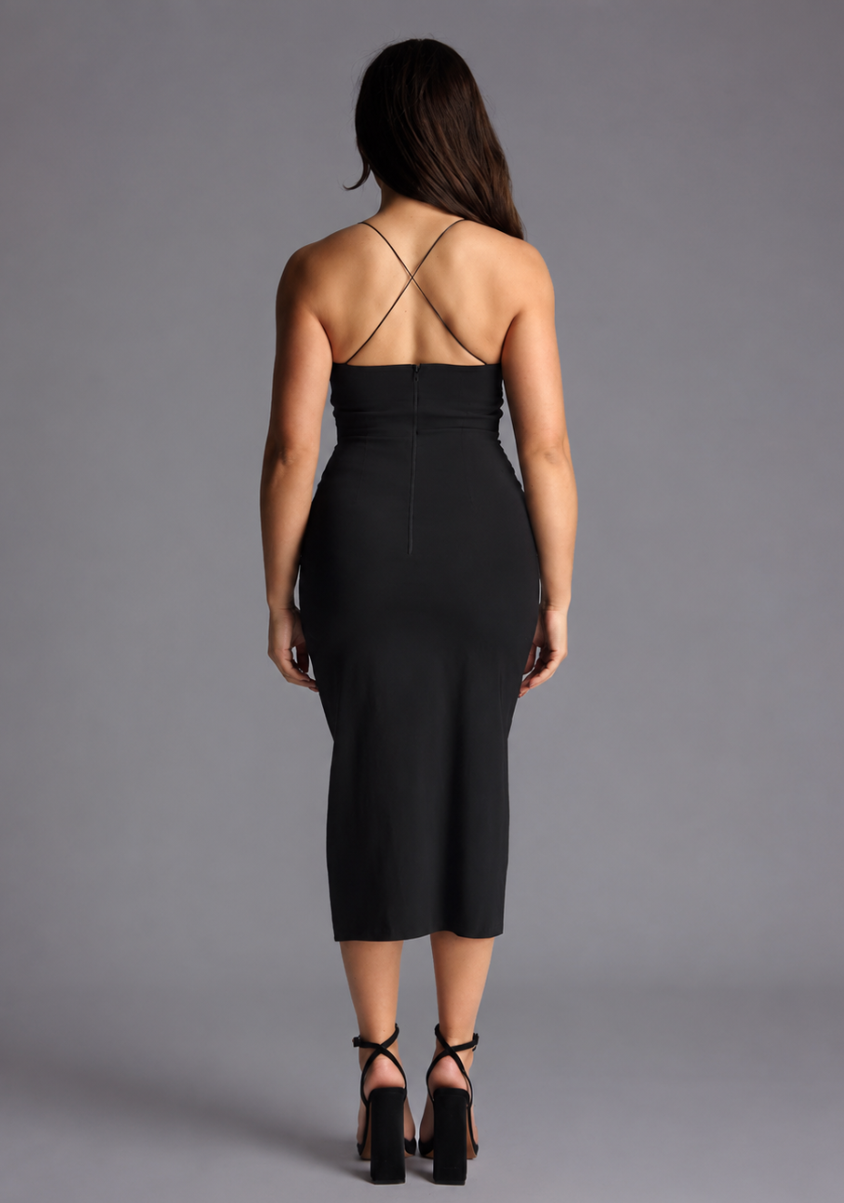 Woman wearing the Vesper Petite beryl black midaxi dress with a thigh slit on a grey background, back view