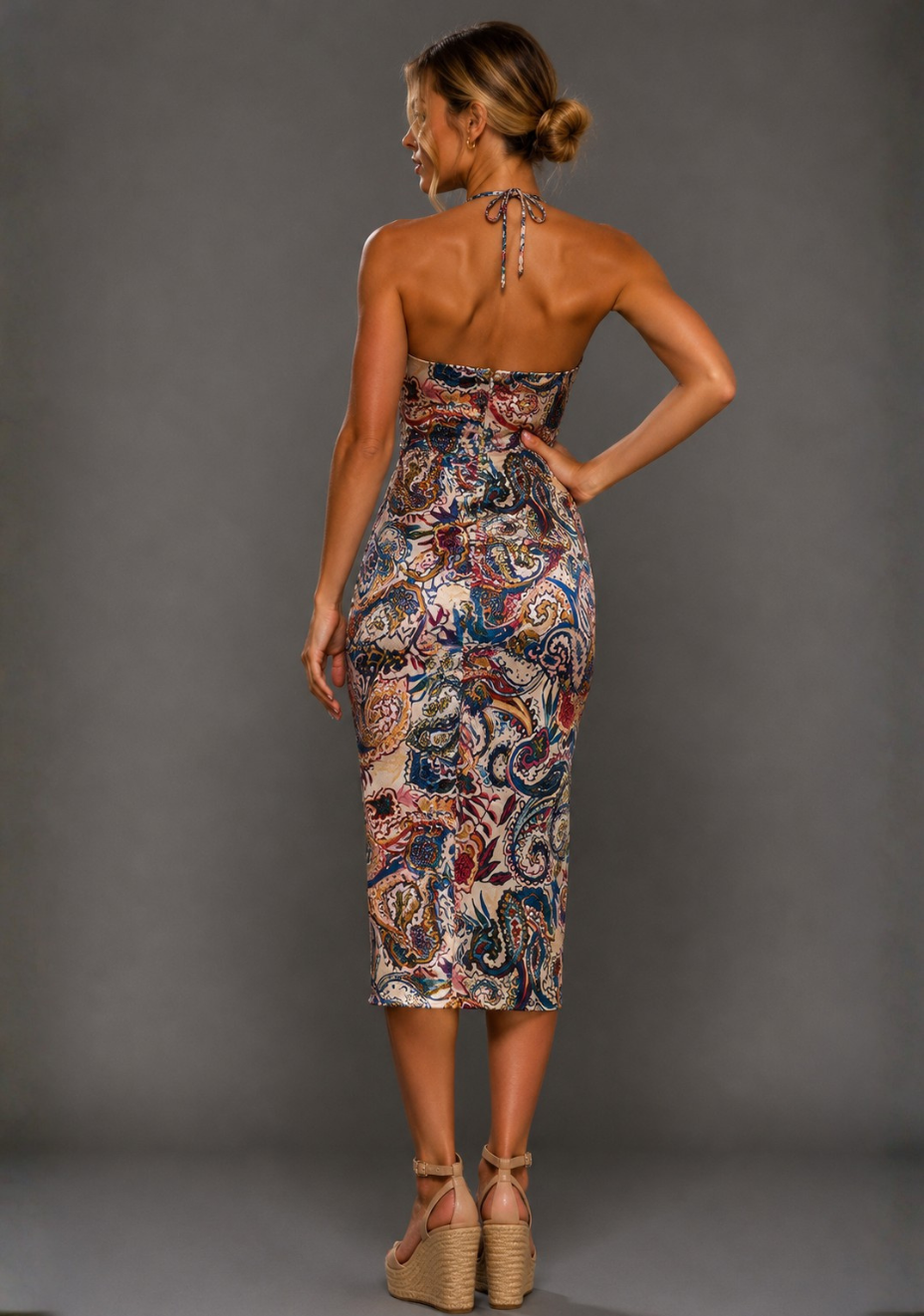 Side back image of a model wearing the VSPR Pandora Paisley Print Midi Dress in Paisley Print, highlighting the tailored fit through the body and elegant midi length, standing against a grey studio backdrop