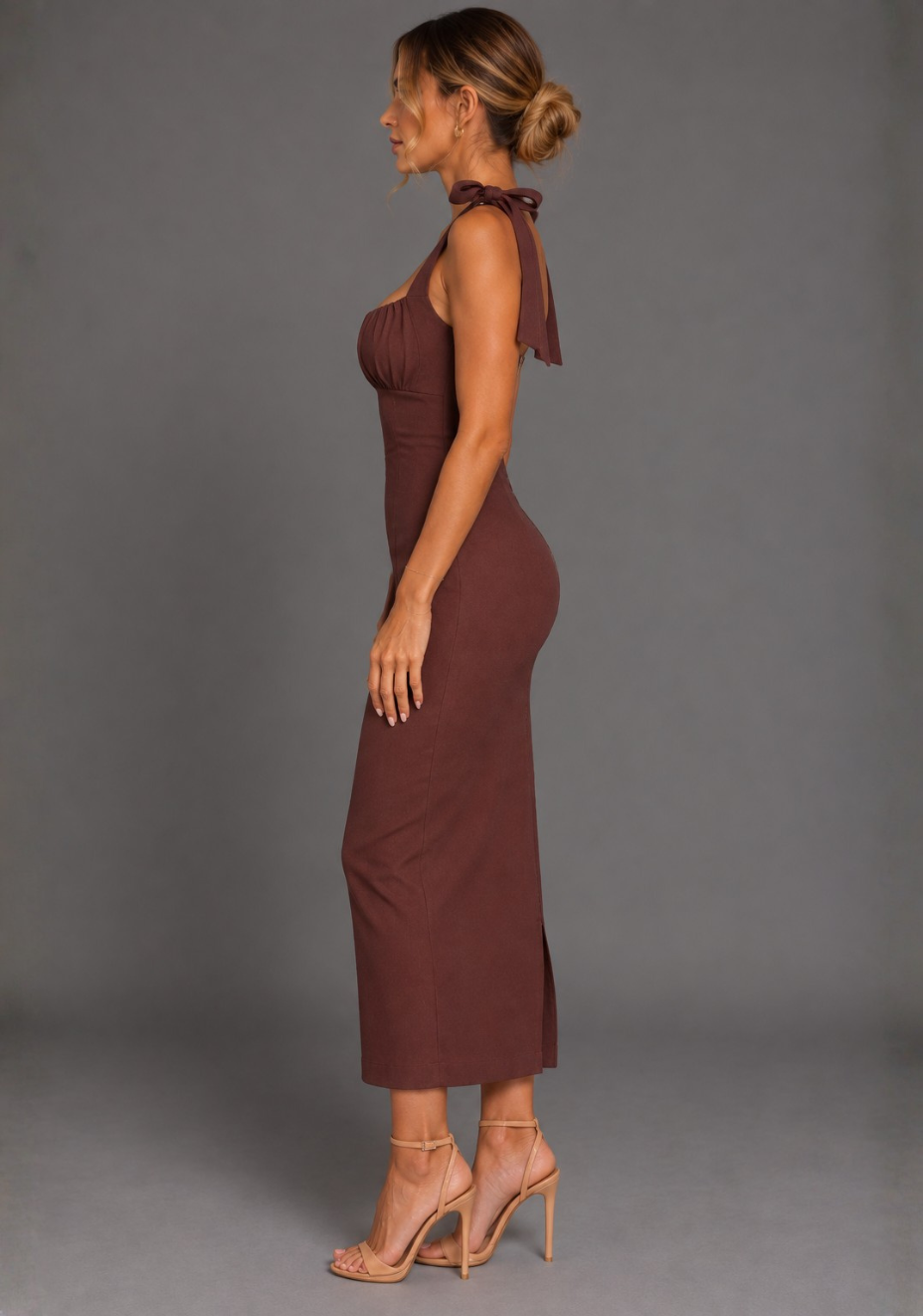 Side back image of a model wearing the VSPR Rapunzel Ruched Bust Bodycon Chocolate Midaxi Dress in Chocolate, showcasing the slim-fit silhouette and elegant midaxi length from the side against a grey studio backdrop.