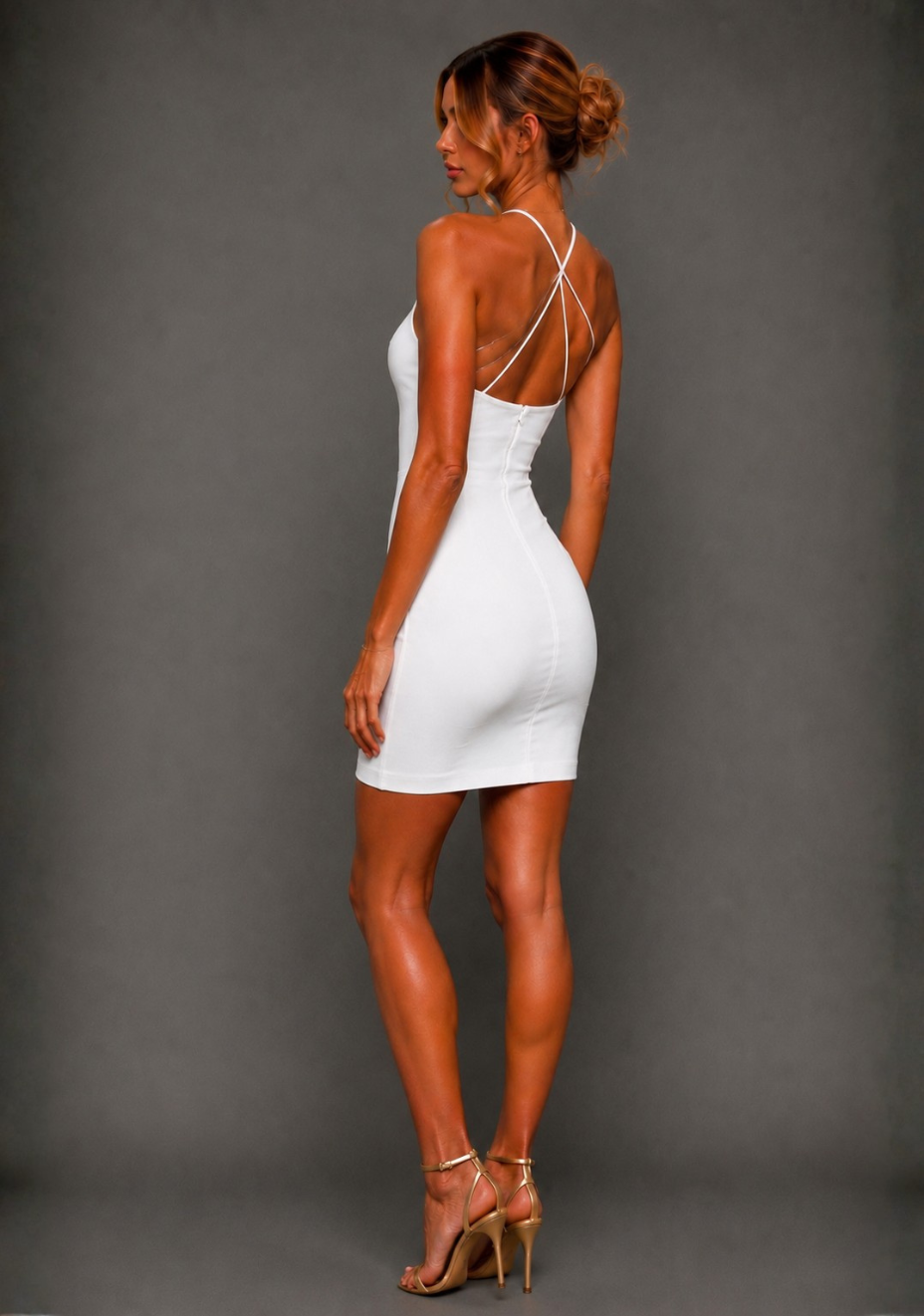 Side back image of a model wearing the VSPR Rumi Ivory Mini Dress from a side back angle, showcasing the striking crossover back straps and sleek figure-enhancing fit against a grey studio backdrop.