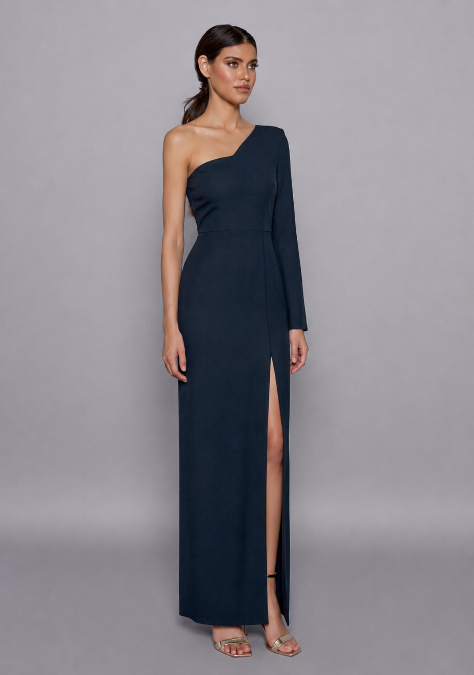 Side-front view of the Vesper Sophia Navy Maxi Dress showcasing the form-fitting silhouette, single sleeve, and fluid front slit that adds graceful movement.