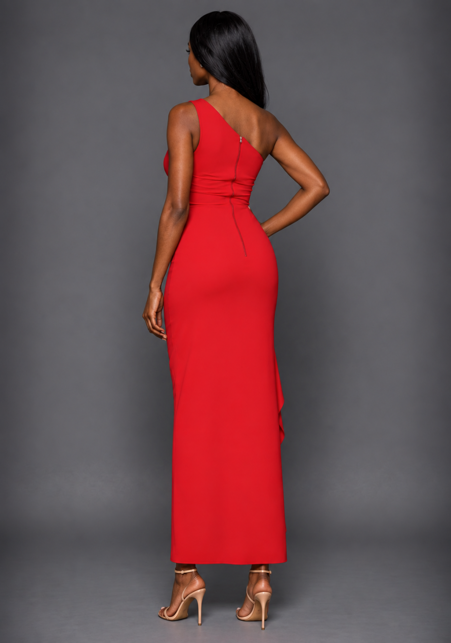 Side back image of a model wearing the VSPR Stella One Shoulder Red Maxi Dress, highlighting its sleek sculpted silhouette and elegant floor-length design against a grey studio backdrop.