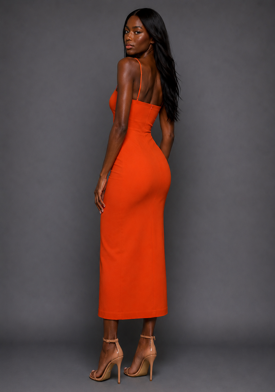 Side back of a model wearing the VSPR Tate Cami Strap Orange Midaxi Dress showcasing the sleek body-skimming fit, elegant silhouette and vibrant orange finish.