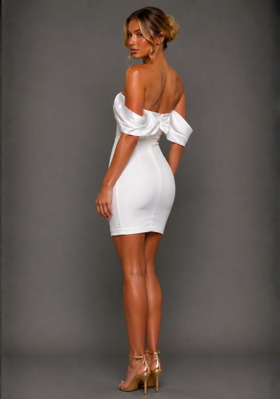 Back angled view of a model wearing the Vesper Paloma Bardot Satin Sleeve Ivory Mini Dress displaying the Bardot neckline and satin sleeves.