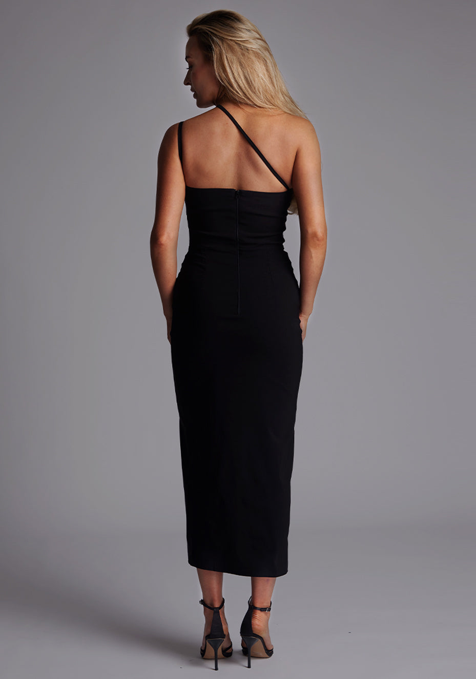 Back image of a model wearing the Vesper Abigail Cross Strap Midaxi Dress in Black, featuring delicate cross straps and a clean, minimalist back design.