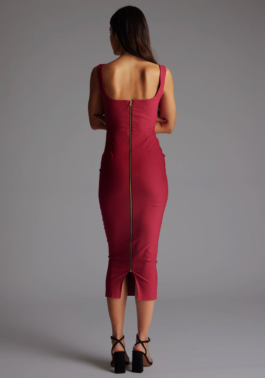Back image of a model wearing the Vesper Andy Square Neck Midaxi Dress in Raspberry, featuring a gold back zip and discreet slit for ease of movement.