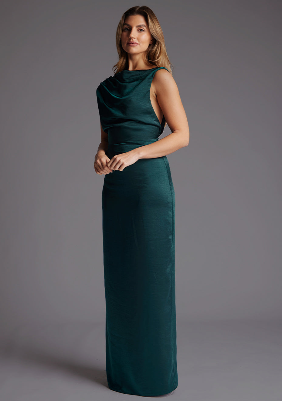 Side front view of model in a pine green satin maxi dress featuring a softly draped high neckline and a smooth, body-skimming silhouette that extends to the floor.
