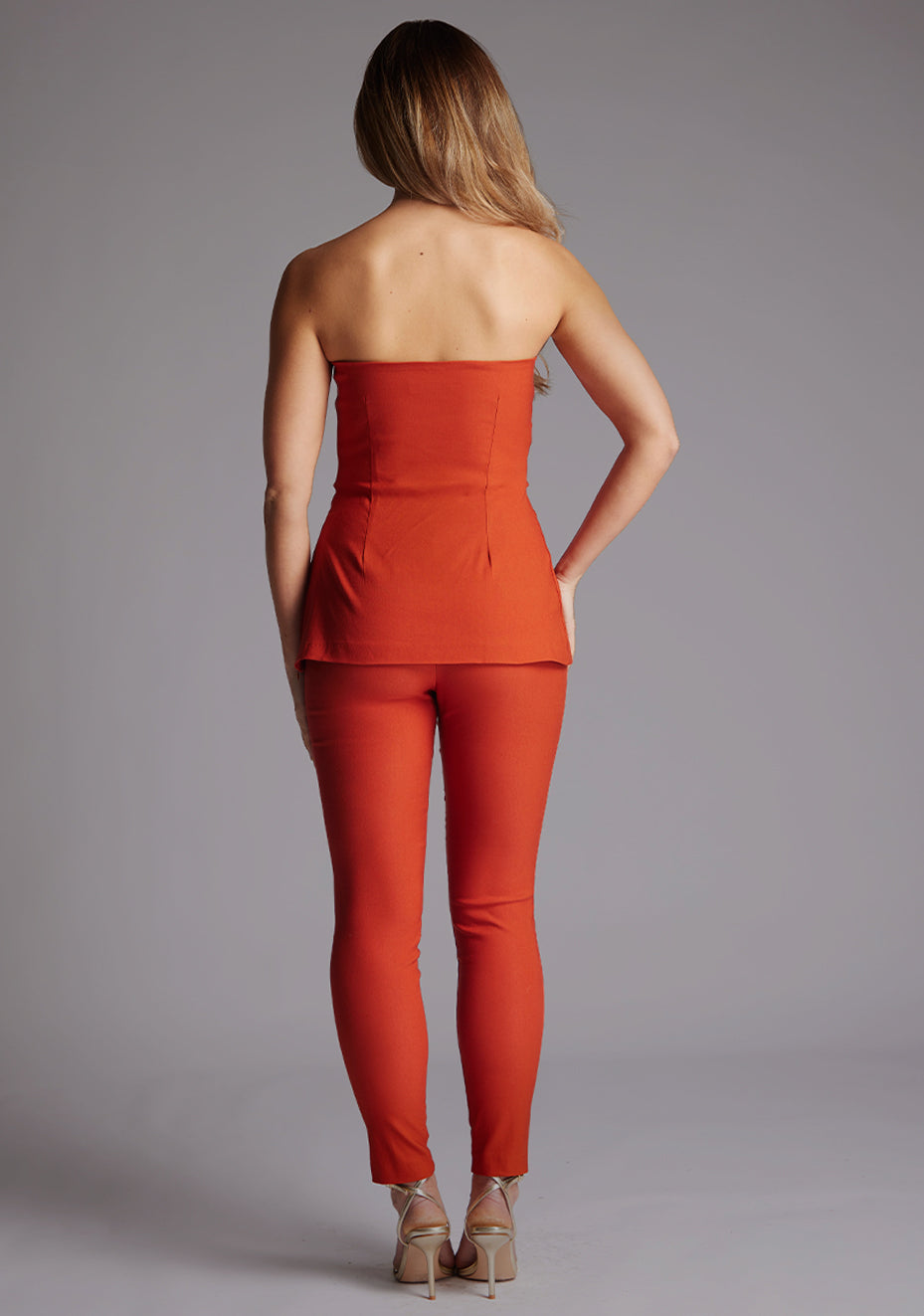 Back image of a model wearing view of the Vesper Augusta Bandeau Longline Top in Rust, highlighting the minimalist strapless design and elegant longline finish.