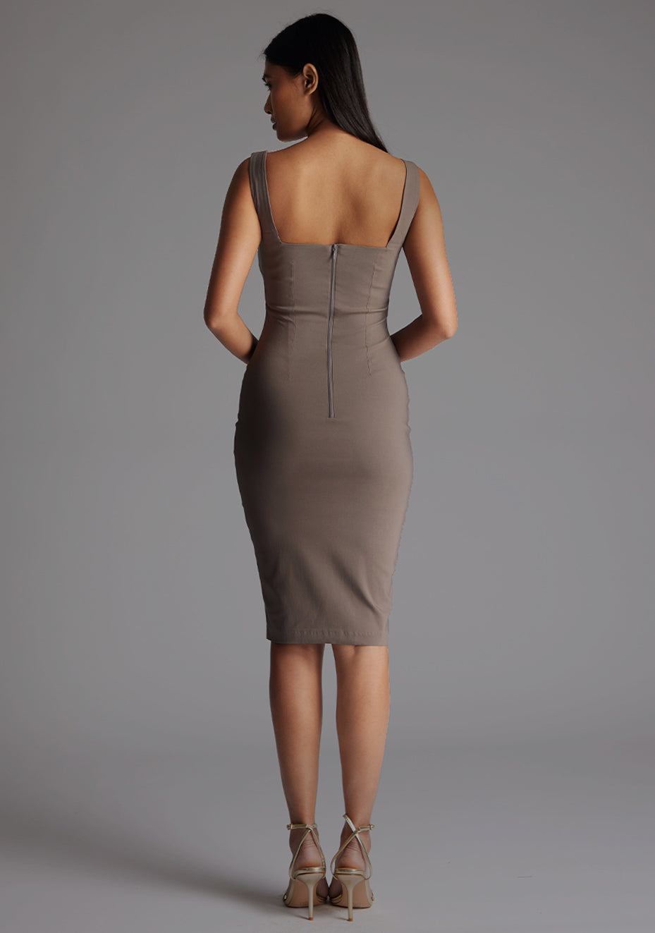 Back image of a model wearing the Vesper Azzura Bodycon Midi Dress in Taupe, highlighting the sleek silhouette and concealed center back zip.