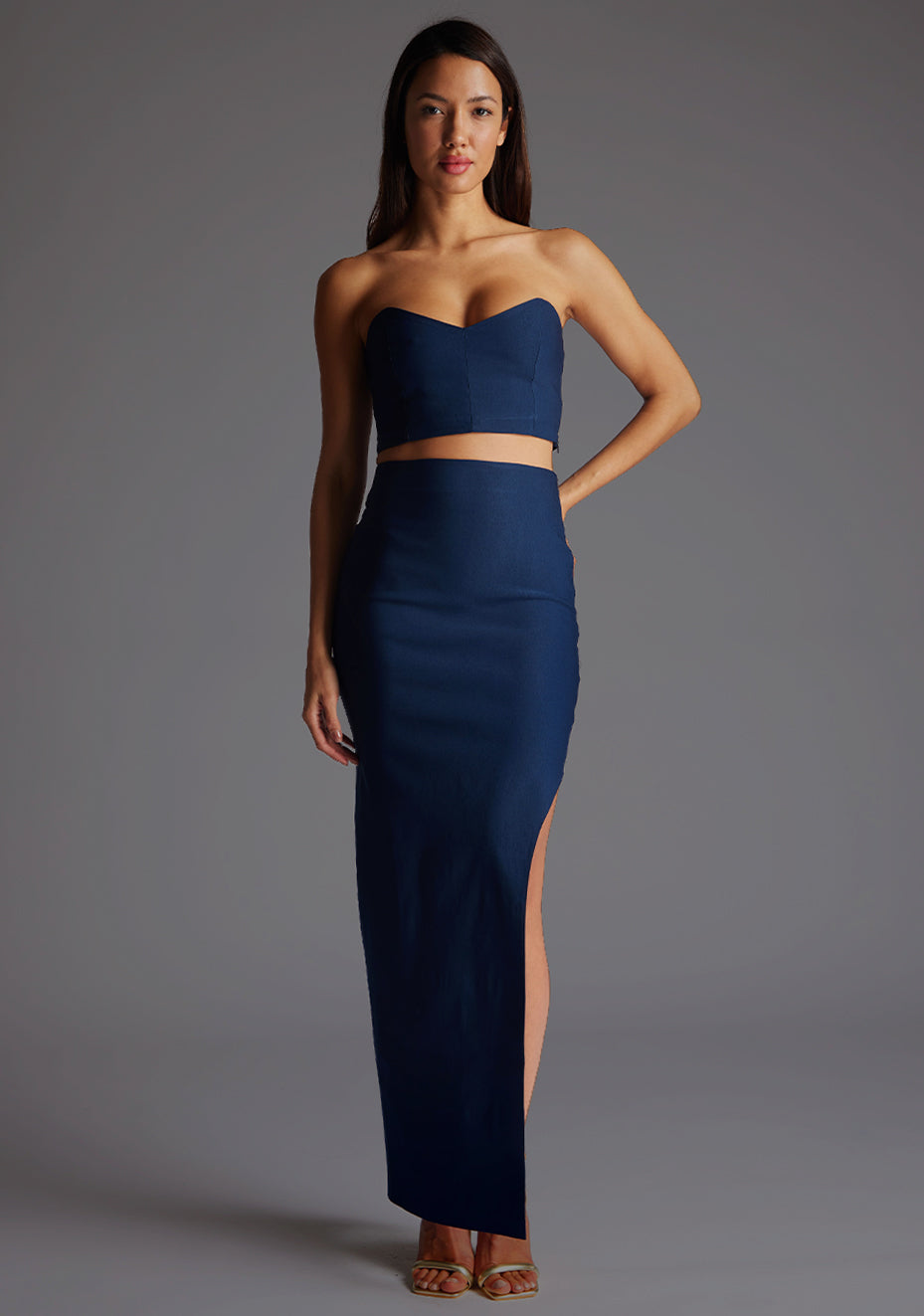 Front image of a model wearing the Vesper Benedetta Strapless Crop Top in Navy with a sculpted strapless silhouette and semi-V neckline, standing against a grey studio backdrop.