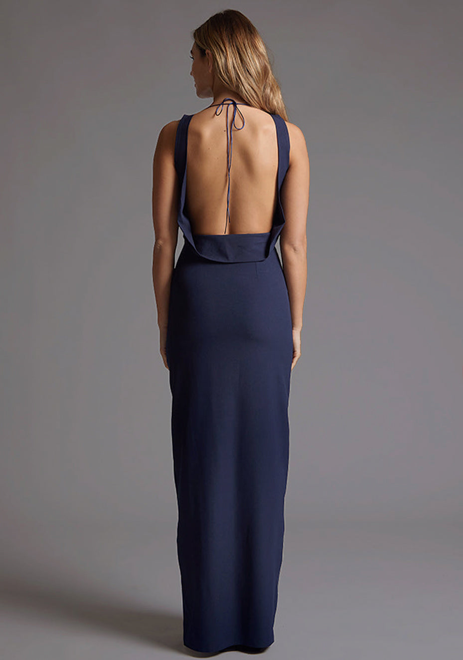 Side back image of the Vesper Brodi Backless Maxi Dress in Navy, emphasizing the graceful open back and flowing maxi silhouette.