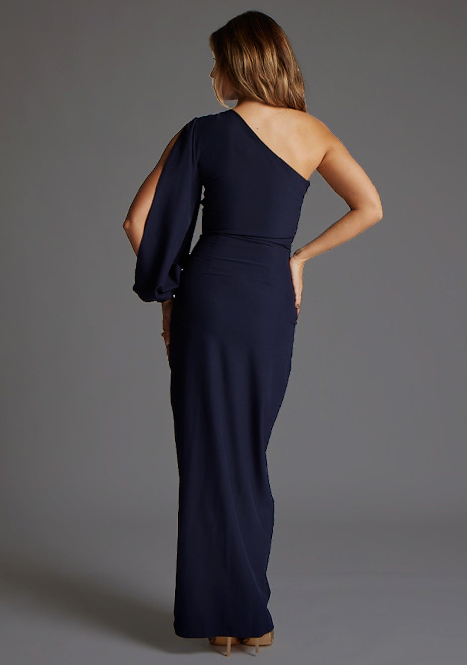 Back image of a model wearing the Vesper Brooklyn One Shoulder Drape Sleeve Maxi Dress in Navy, featuring a sleek open shoulder line and streamlined maxi silhouette.