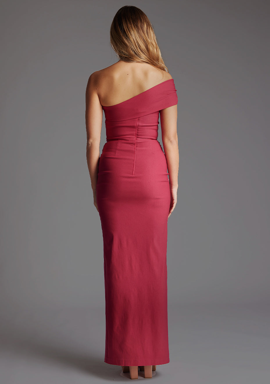 Back image of a model wearing the Vesper Carmel Off-the-Shoulder Maxi Dress in Raspberry, displaying the clean back finish, sophisticated off-shoulder design and elongated maxi silhouette.