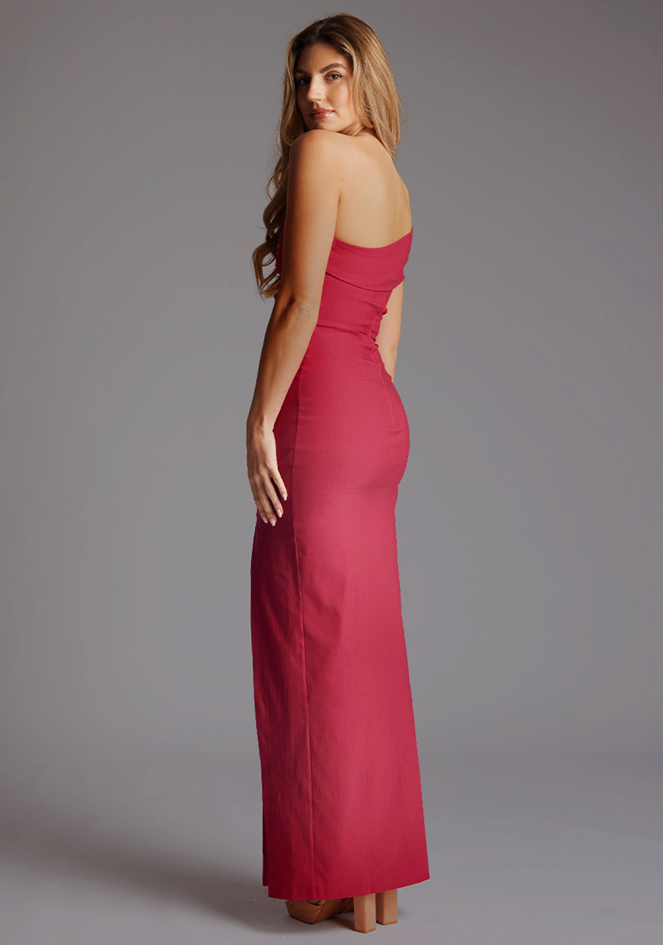 Side back image of a model wearing the Vesper Carmel Off-the-Shoulder Maxi Dress in Raspberry, revealing the smooth back finish and elegant maxi length.