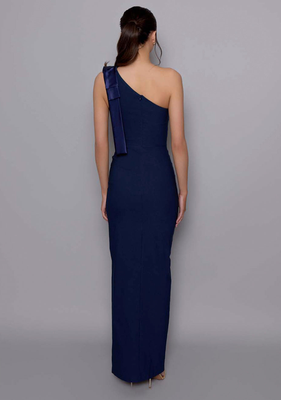 Back view of the VSPR Cedar dress revealing the fitted back panel and precise tailoring along the side seam, with the bow shoulder detail visible from the angle.