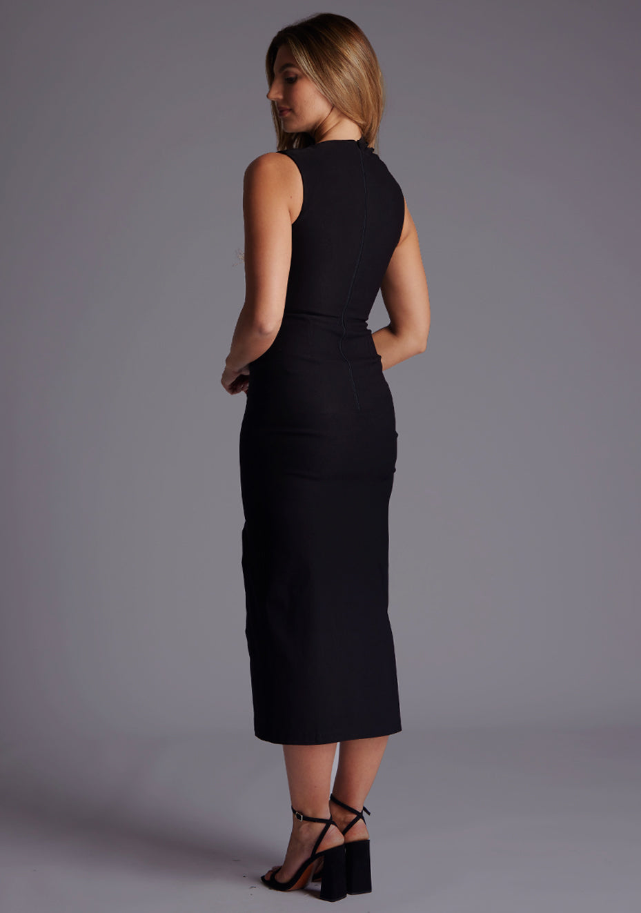 Side back image of a model in the Vesper Clarice High Neck Ruched Midaxi Dress in Black showing the smooth back line and fitted shape.