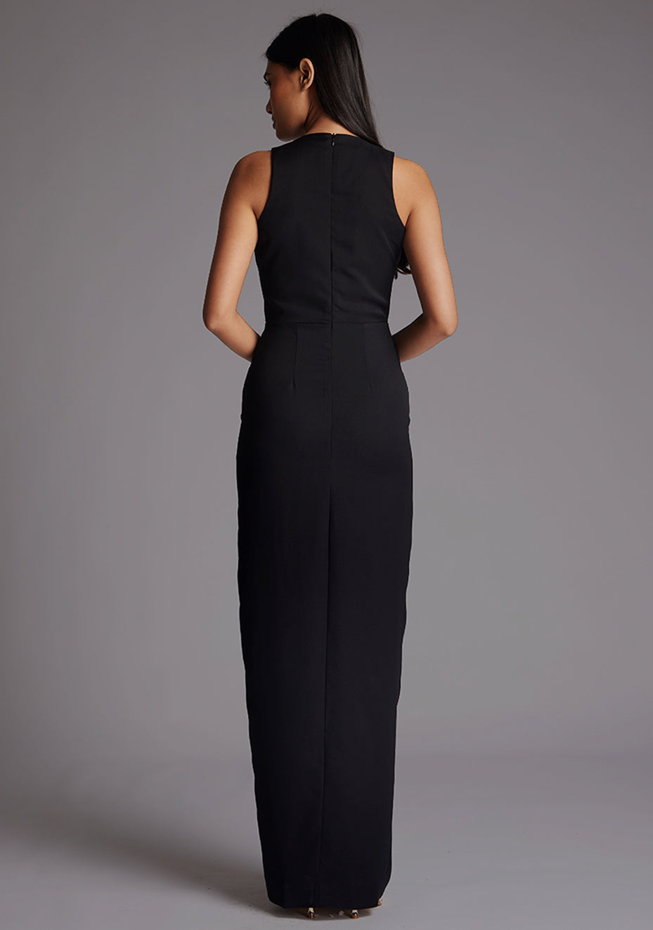 Back image of a model wearing a black sleeveless maxi dress with   sleeveless design and flattering V-neckline accentuates your figure while the body con fit gracefully hugs your curves. The design featured is the Vesper Elba V-neckline Maxi Dress in Black.