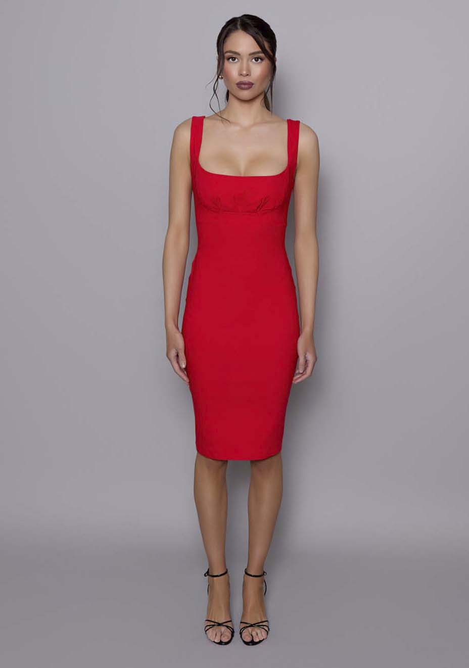 Model wearing the VSPR Evette red midi dress featuring a square neckline, wide straps, and ruched bust detail, styled against a grey studio backdrop.