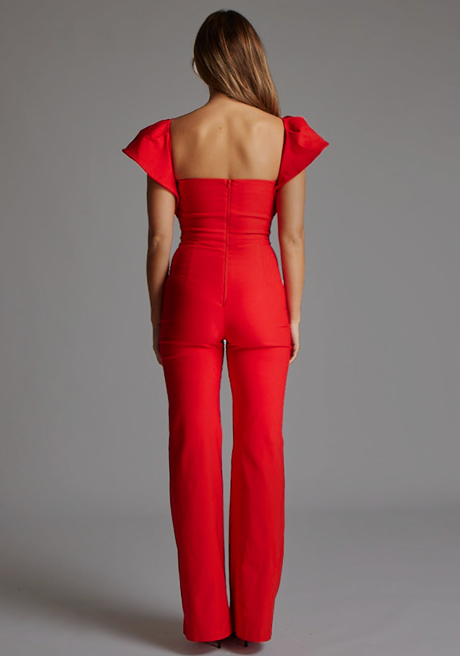 Back image of a model wearing the Vesper Leigh Wide Leg Frill Sleeve Jumpsuit in Red, featuring a clean back finish with a discreet zip and wide-leg silhouette.