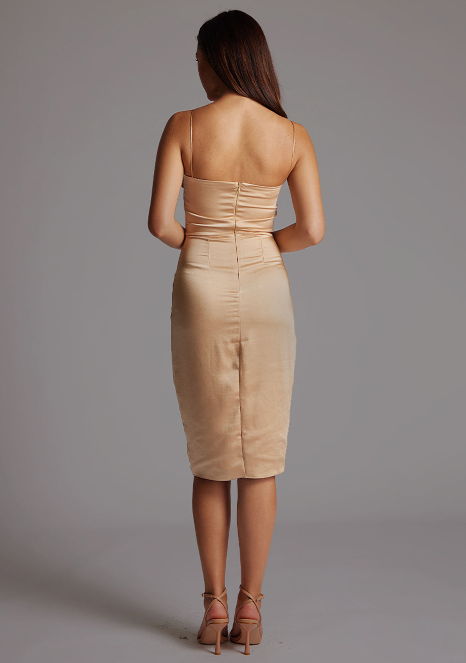 Back image of a model wearing the Vesper Lisa Satin Midi Dress in Champagne on a model, highlighting the smooth satin fabric, minimal strap design, and flattering midi length.
