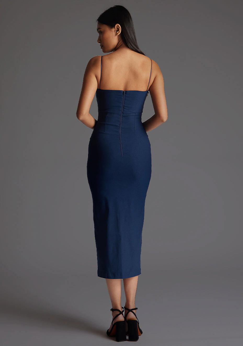 Back image of  model wearing a navy strappy midaxi dress with a sweetheart neckline, thin straps, centre front skirt split and centre back zip for a perfect fit. The design featured is the Vesper Miren Strappy Bodycon Midaxi Dress in Navy.