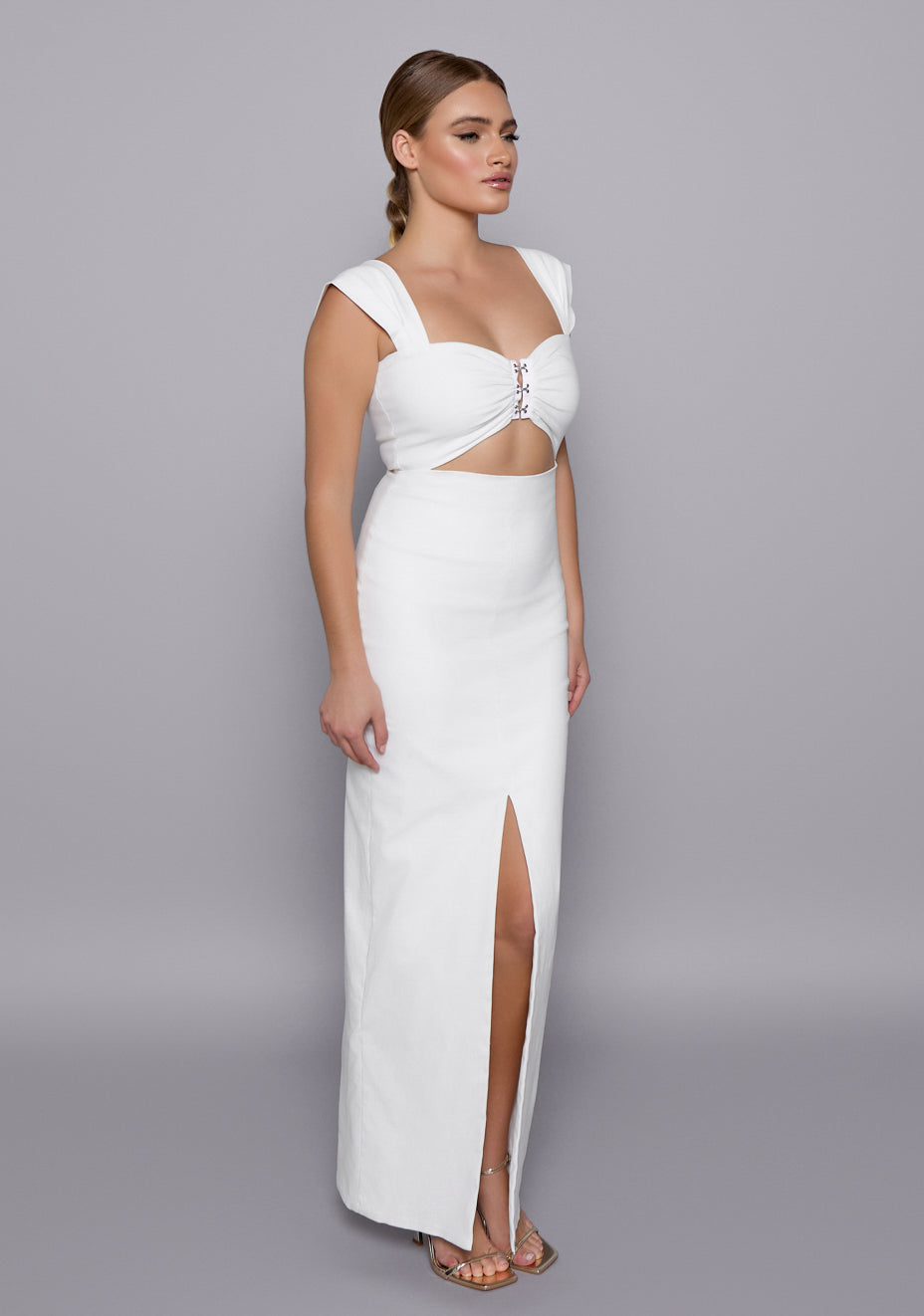 Side-front view of the VSPR Morgan Ivory Maxi Dress highlighting the underbust cutout, cap sleeves, and body-skimming fit with a graceful slit, capturing the modern two-piece illusion.