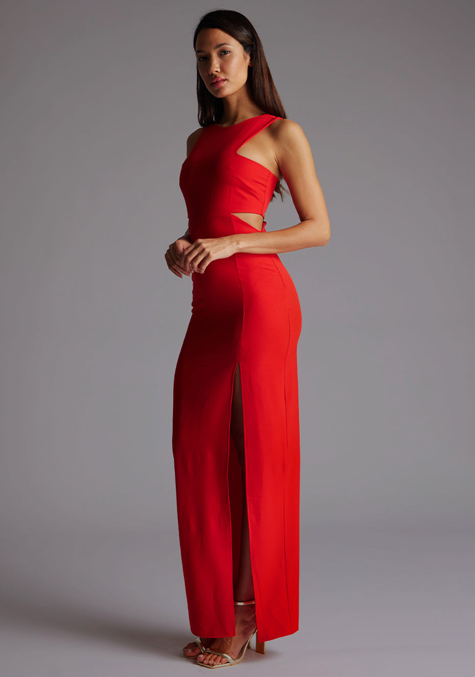 Side front image of a model wearing the Vesper Paige Cut Out Maxi Dress in Red, showcasing the waist cut-outs and flowing max.