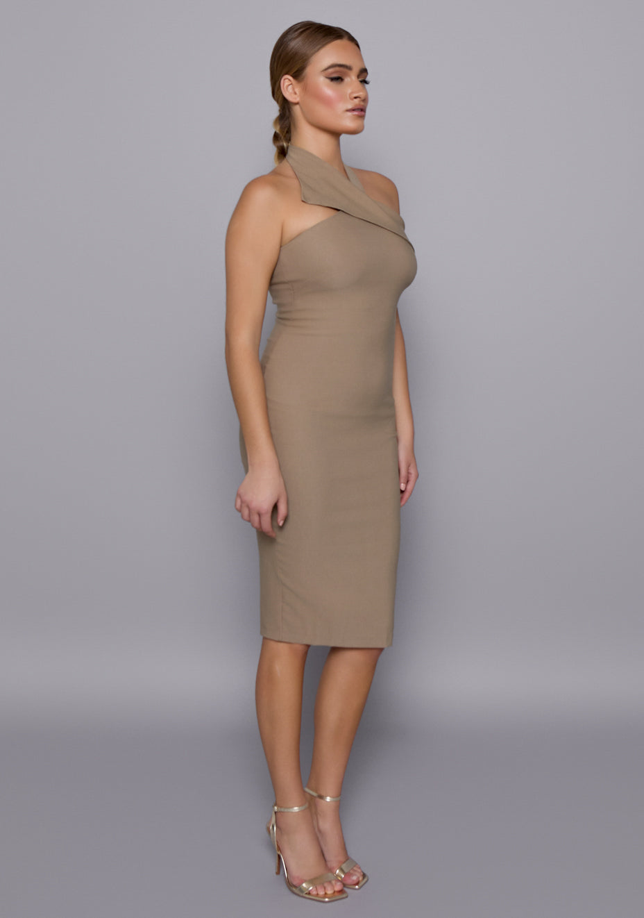 Side-front view of the VSPR Petra Taupe Midi Dress showcasing the curve-skimming fit, structured halterneck, and clean lines down the torso.