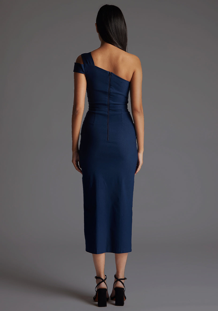 Back image of a model wearing the Vesper Porscha One Shoulder Midaxi Dress in Navy, highlighting the seamless zip closure and elegant fitted design.