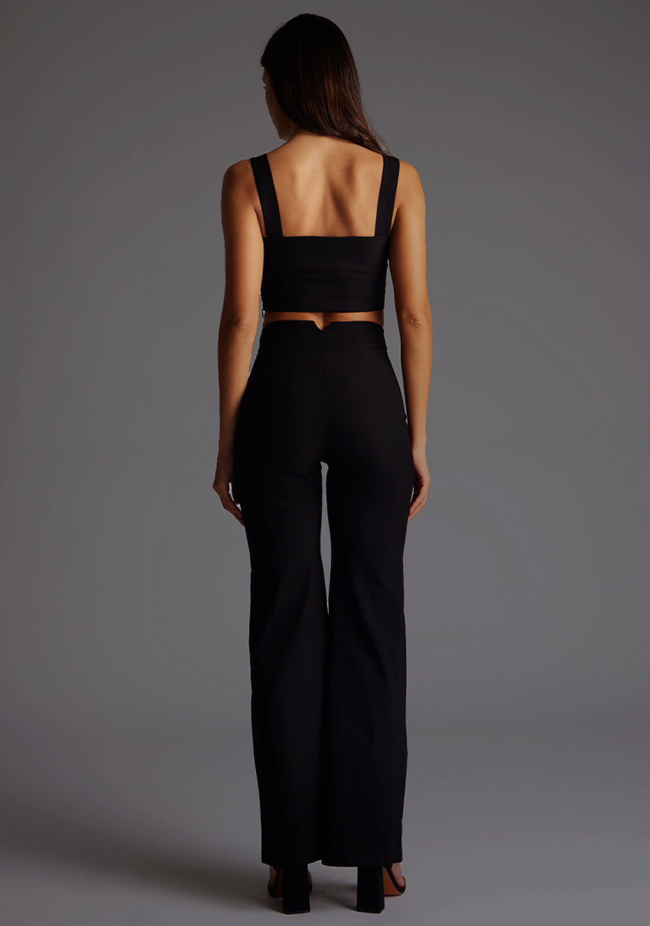 Back image of a model wearing a black crop top with a sweetheart neckline and thick straps. The design featured is the Vesper Sweetheart Neckline Crop Top in Black pair with Vesper June Wide Leg Trousers in Black.