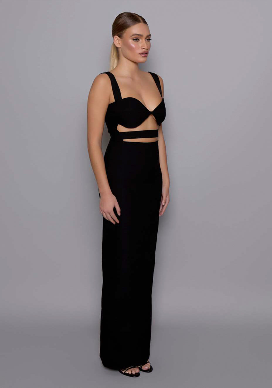 Side-front view of the VSPR Solene black maxi dress with a full-length column skirt, wide straps, and sculpted bodice creating a flattering silhouette.