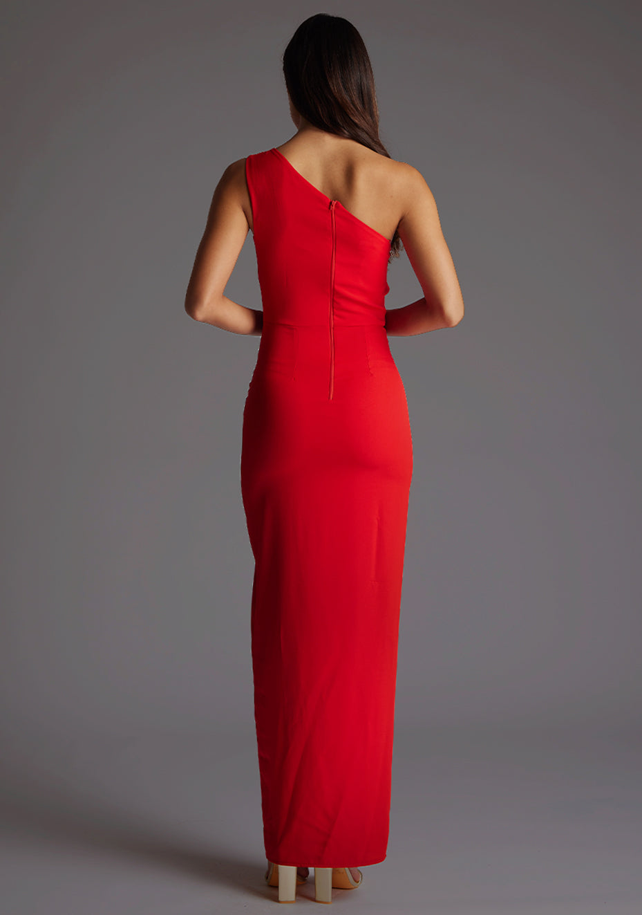 Back image of model wearing red asymmetric maxi dress with a asymmetric neckline with one shoulder detail, front bodice cut-out and front skirt split. The design featured is Vesper Verity Red Asymmetric Maxi Dress