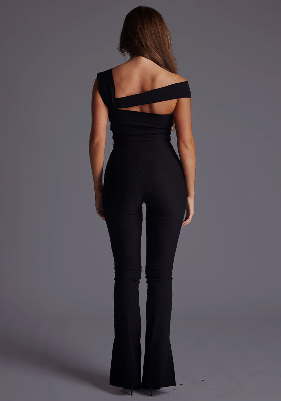 Back image of a model wearing a black trousers with a flattering slim-fit cut and a unique slit ankle design, adding a touch of edge to your look. The design featured is the Vesper Kemi Black Trousers pair with Vesper Angel Black Top
