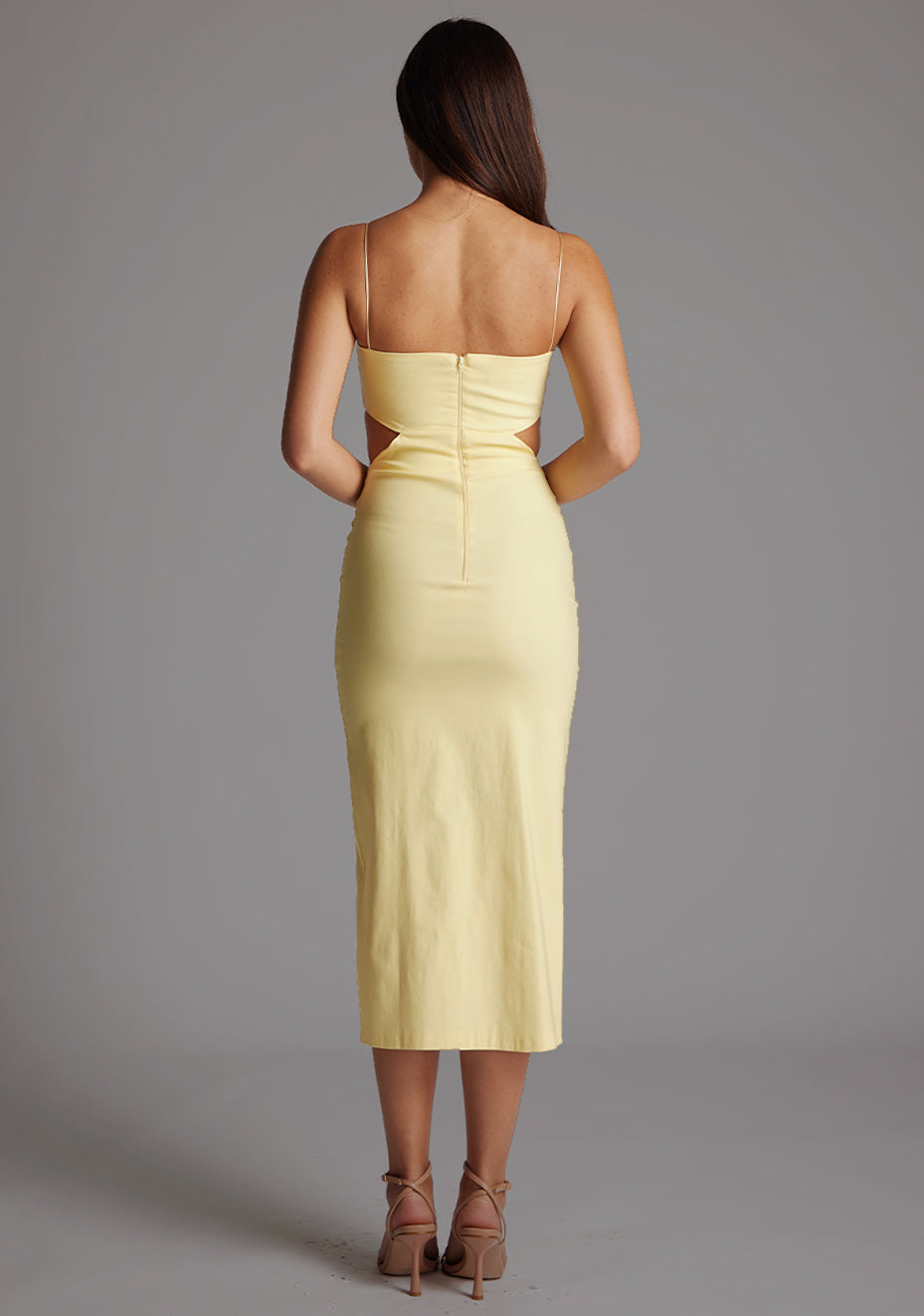 Back image of a model wearing a yellow midaxi dress with a graceful scoop neckline, slender straps, subtle side cut-out and it offers both mobility and modern flair with a front skirt split. The design featured is the Vesper Marilynn Yellow Midaxi Dress