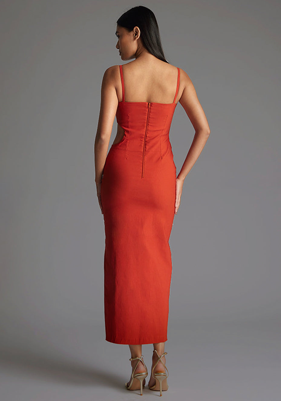 Back image of the model wearing a rust midaxi dress with a scoop neckline, bodycon silhouette, side cut out and front skirt split . The design featured is the Vesper Maryam Rust Midaxi Dress.