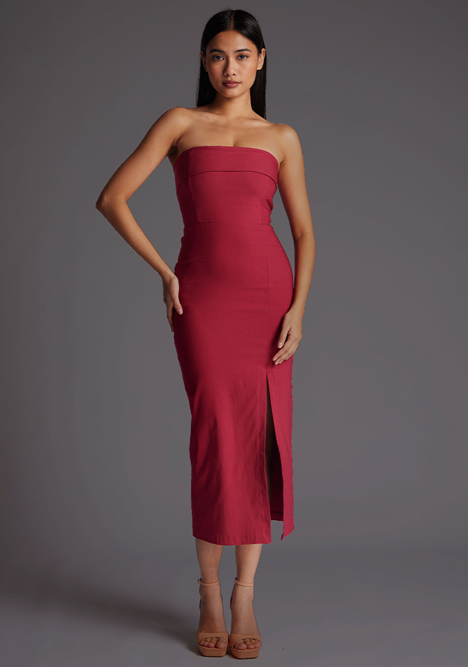 Front image of a model wearing a raspberry midaxi dress with a straight-across strapless design, side slit and bodycon fit. The design featured is the Vesper Monica Strapless Midaxi Dress in Raspberry
