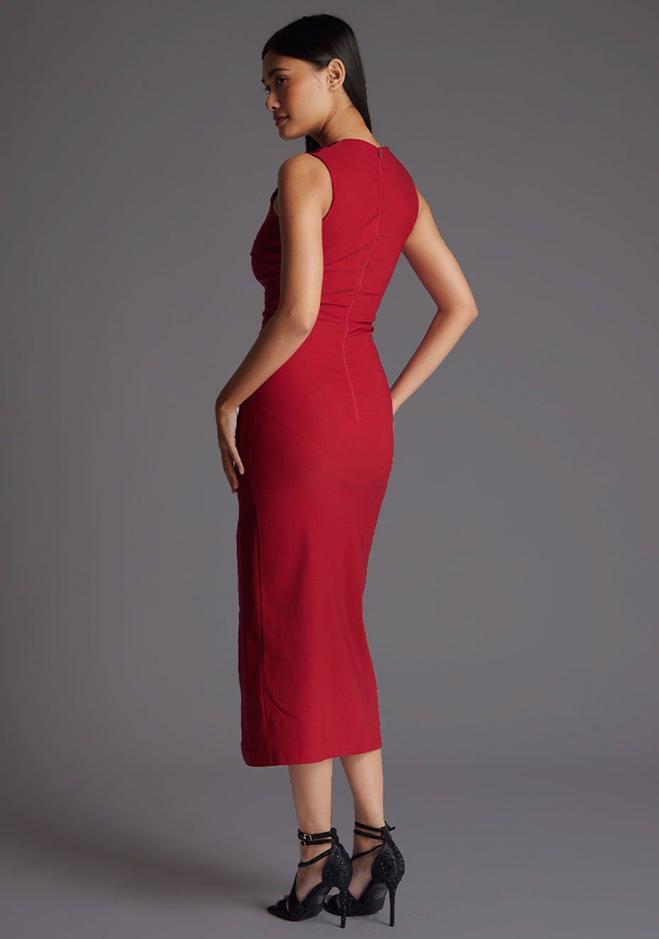 Back quarter image of model wearing a wine midaxi dress with a asymmetric neckline, front cutout detail, front skirt split and center back zip. The design featured is the Vesper Queenie Wine Midaxi Dress.