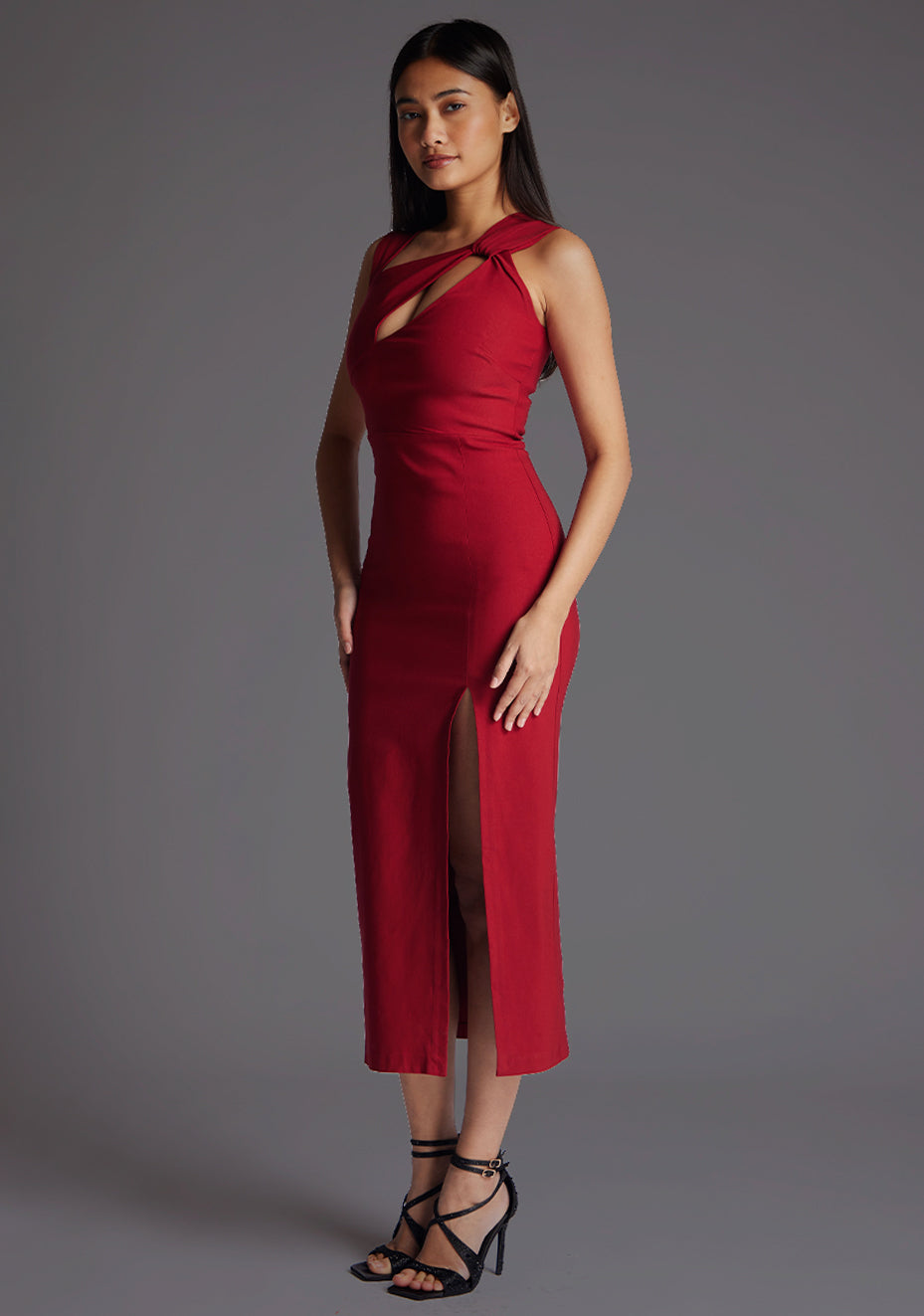 Front quarter image of model wearing a wine midaxi dress with a asymmetric neckline, front cutout detail, front skirt split and center back zip. The design featured is the Vesper Queenie Wine Midaxi Dress.