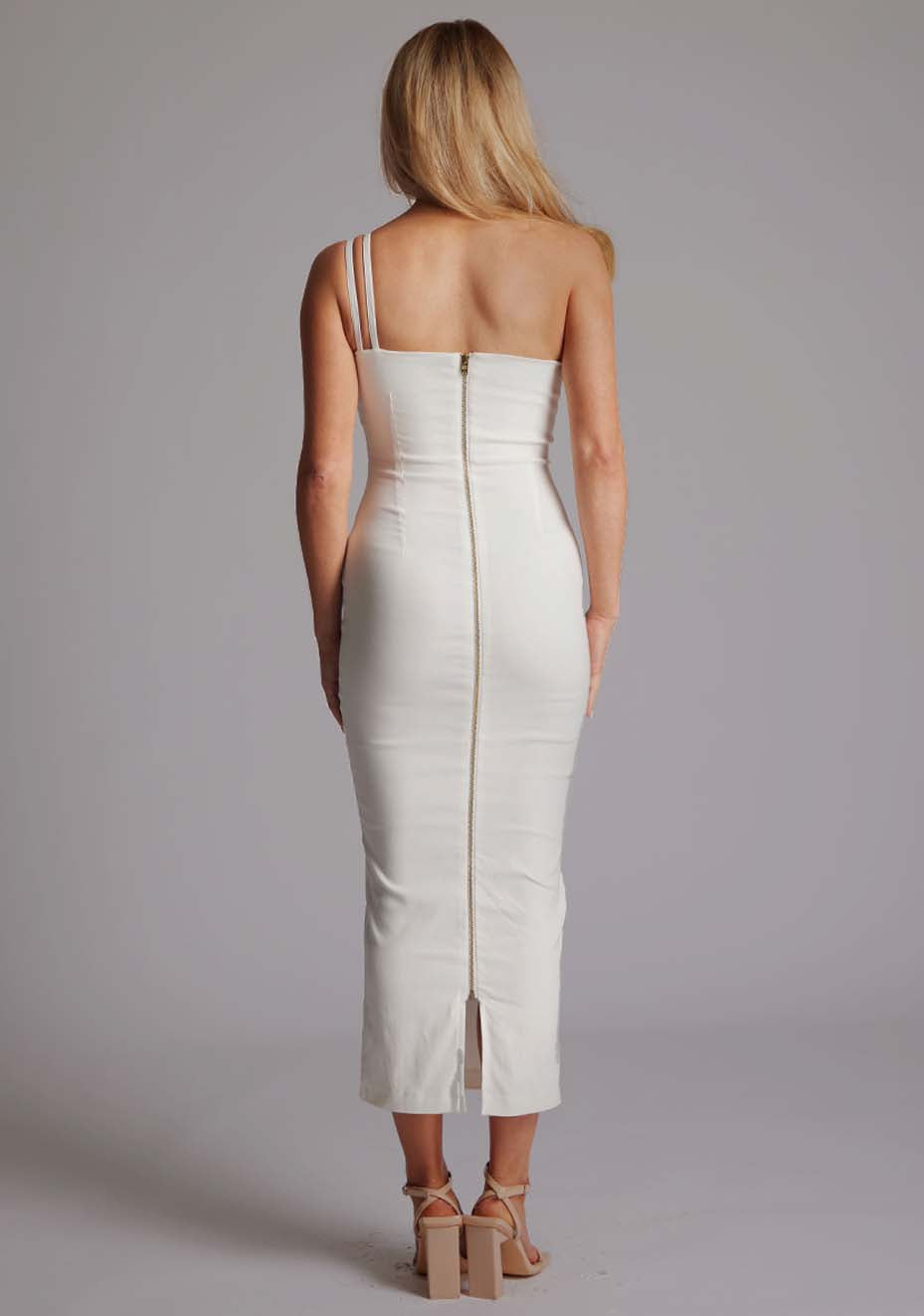 Back image of blonde model wearing a ivory midaxi dress with an unique one-shoulder design, asymmetric neckline with a small cut-out and a bodycon fit, finished with a statement centre back gold zip. The design featured is the Vesper Tasha Ivory One Shoulder Midaxi Dress.