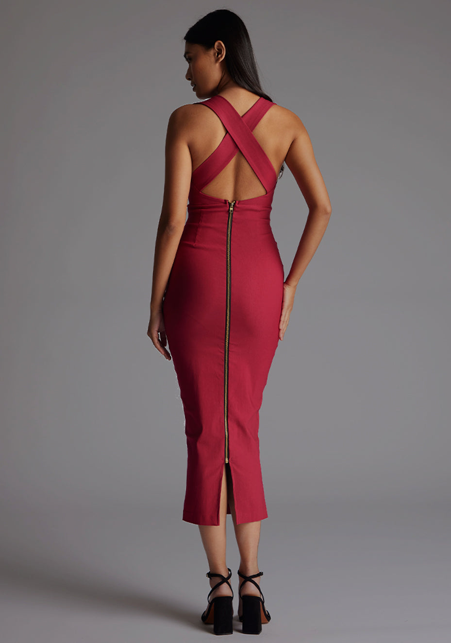 Back image of a model wearing a raspberry midaxi dress with a stunning sleeveless masterpiece, plunging v-neckline ,slim silhouette and cross back and gold zip at the back. The design featured is the Vesper Verona Raspberry Midaxi Dress