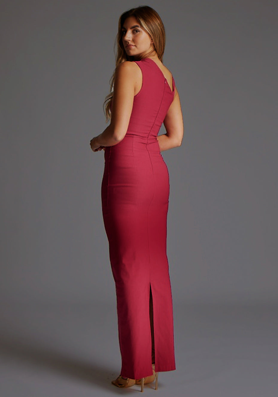 Back quarter image of a model wearing a raspberry asymmetric maxi dress with a asymmetric neckline silhouette, back skirt split and ruched detailing enhances the dress's allure. The design featured is the Vesper Wyatt Raspberry Asymmetric Maxi Dress.