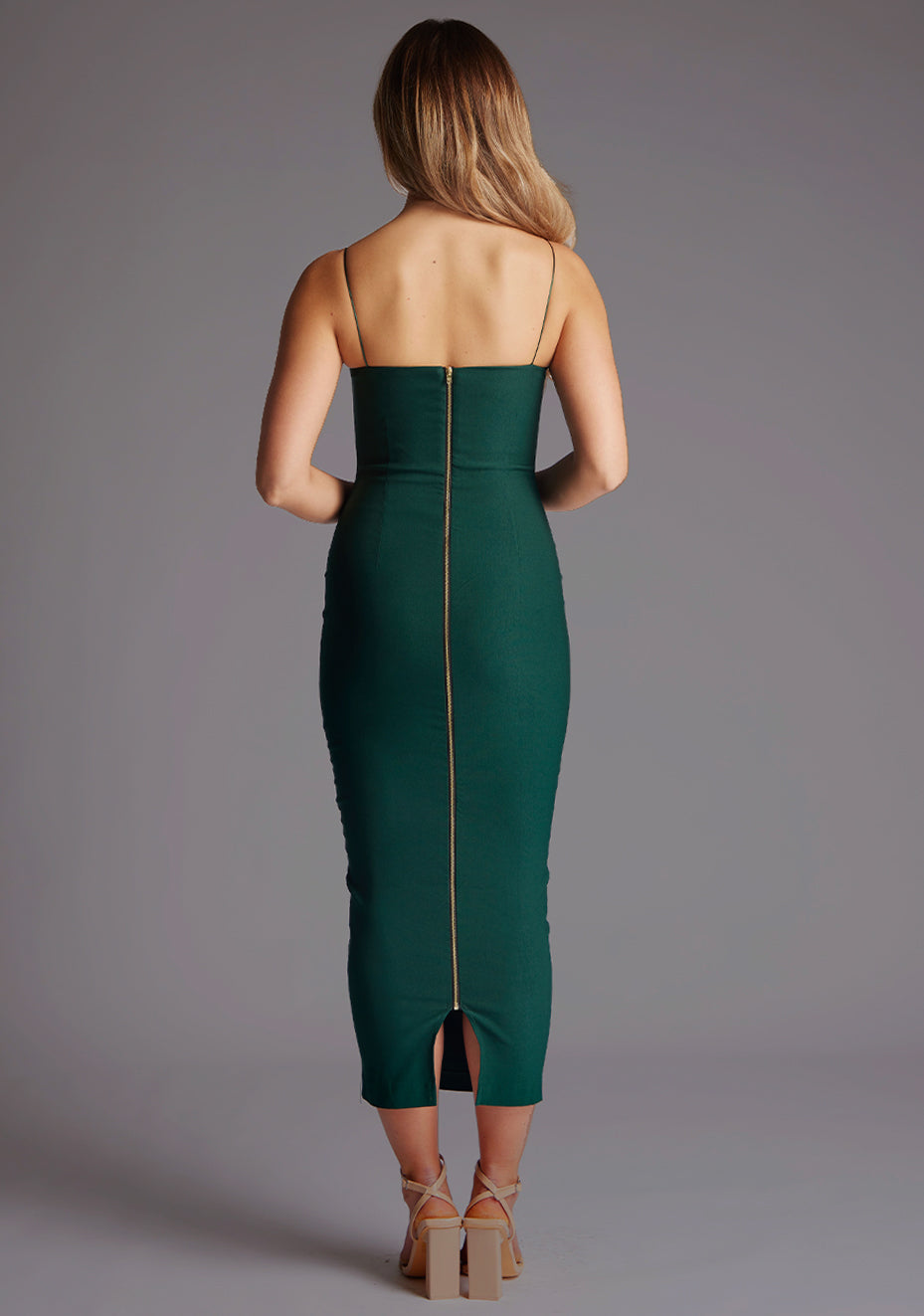 Back image of a model wearing the VSPR Zendeya Scoop Neckline Forest Green Midaxi Dress highlighting the sleek back profile, elegant fit, and midaxi length against a grey studio backdrop.