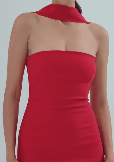 Model posing and turning in the VSPR Dion Red Midaxi Dress, showcasing the straight neckline with collar detailing, unique back straps, and gold center-back zip; the bodycon silhouette accentuates the figure while the bold red color adds a striking, standout effect, paired with strappy heels in a minimal studio setting.